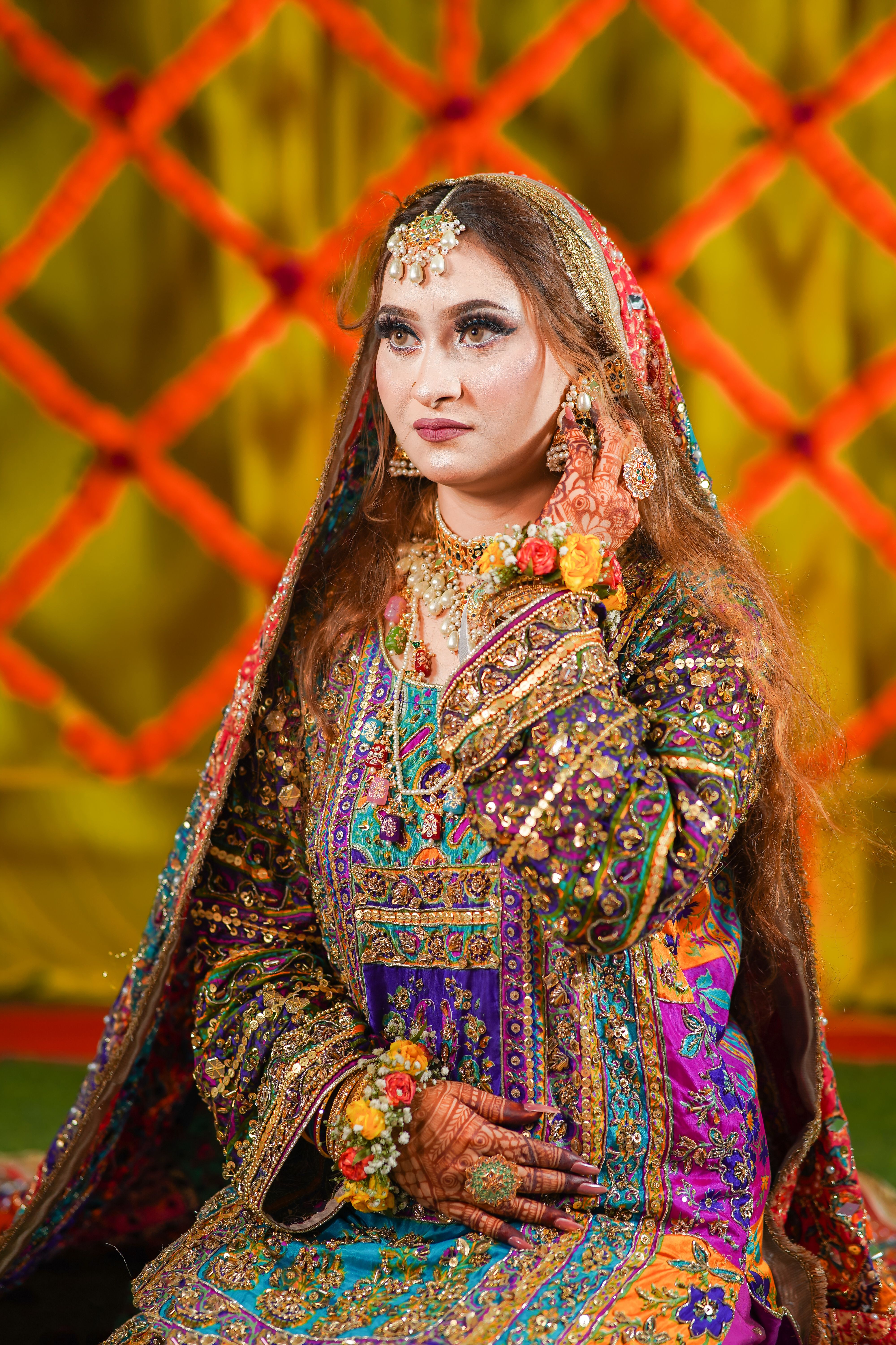 Vibrant South Asian bride adorned in colorful traditional attire and jewelry, showcasing cultural beauty.