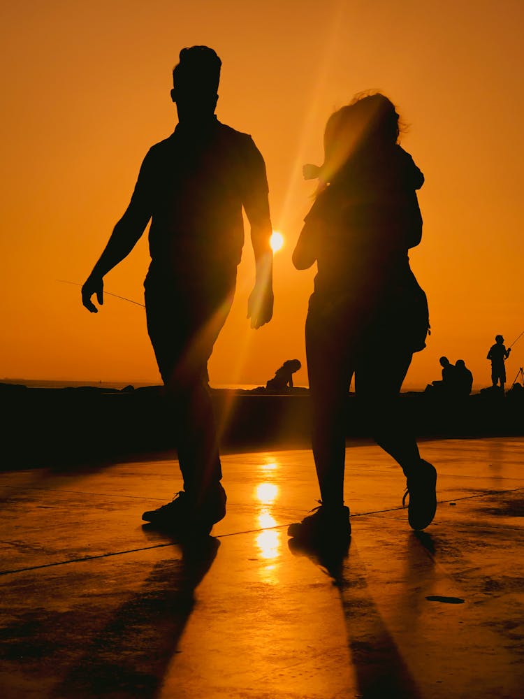 Silhouette Of Couple With Child Walking At Dusk