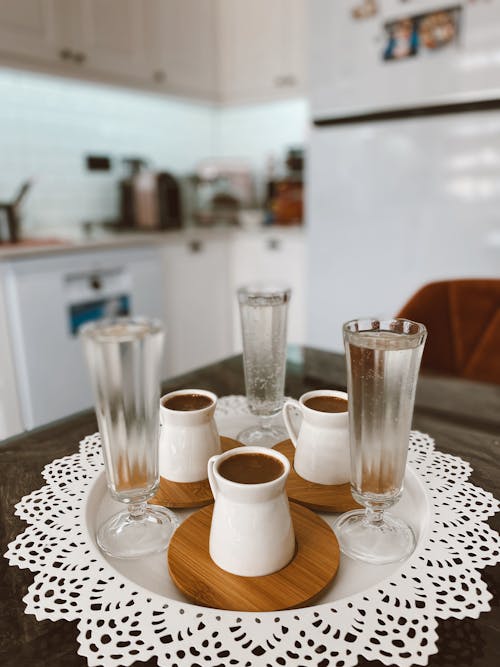 A table with three glasses and a doily