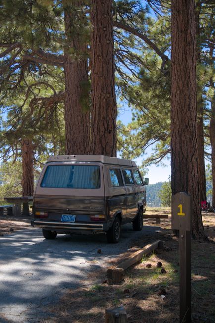 Sunrise over an empty California campground with pine trees, tent pads, and a reservation kiosk