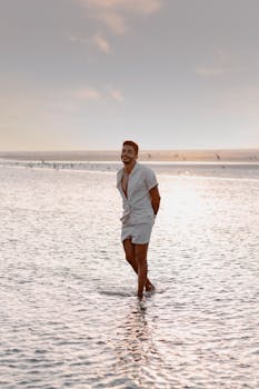 Smiling man wading in ocean, enjoying a sunny day at São Luís beach.