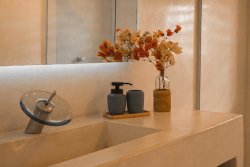 A bathroom with a sink and a vase of flowers