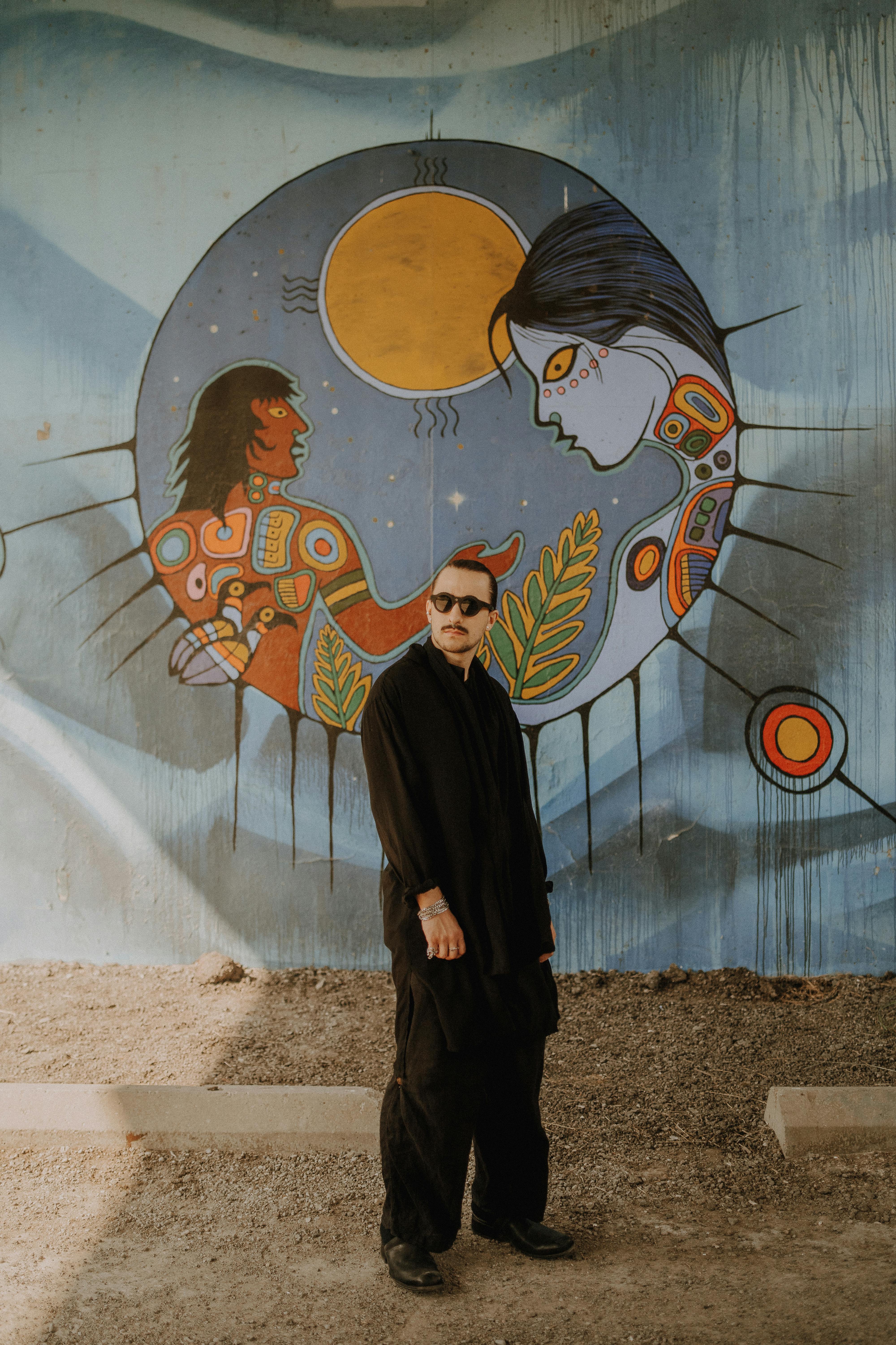 a man in black standing in front of a mural