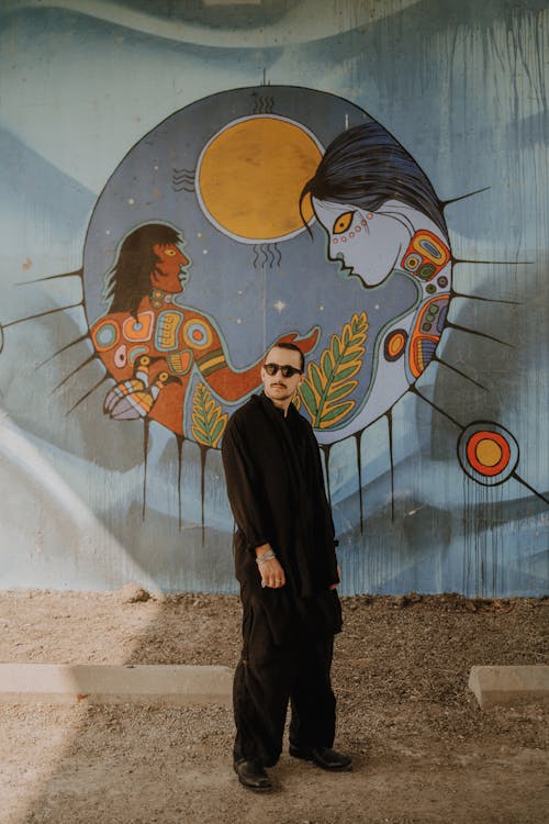 Free A man in black standing in front of a mural Stock Photo