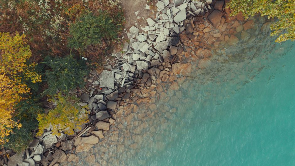 Spectacular Private 20 Minute River Ride Tour Review: Soaring Over Detroit's Iconic Waterway Review 2026 - A breathtaking aerial view of a rocky shoreline with turquoise water and lush autumn foliage.