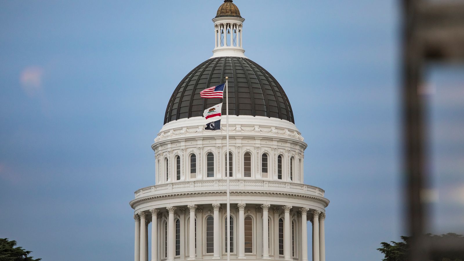 View of California State Capitol dome with American and state flags.