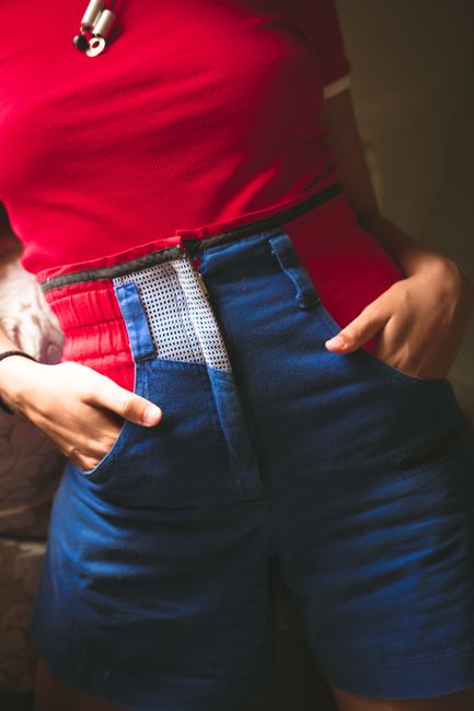 Stylish red top with blue shorts and unique waistband detail.