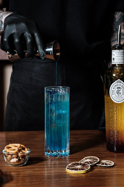 Hand in Glove Pouring Drink to Blue Cocktail