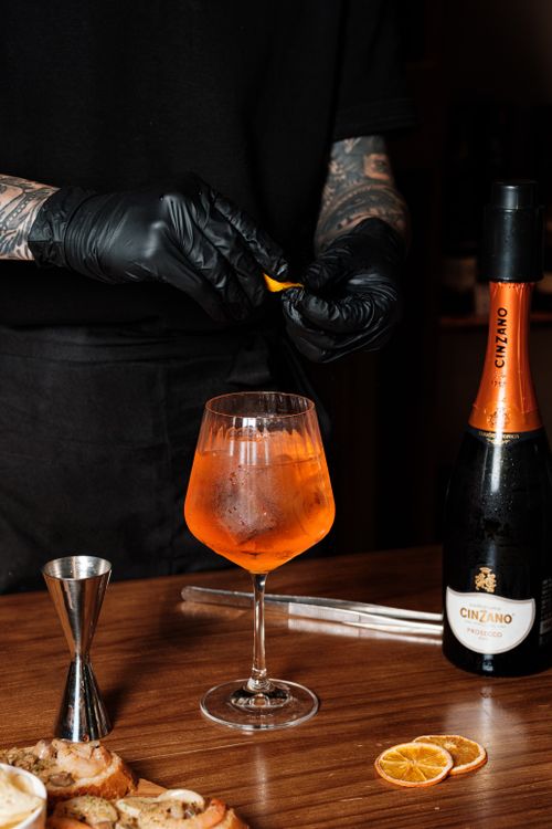 Free A bartender skillfully prepares an Aperol Spritz, showcasing the vibrant drink with an orange garnish. Stock Photo