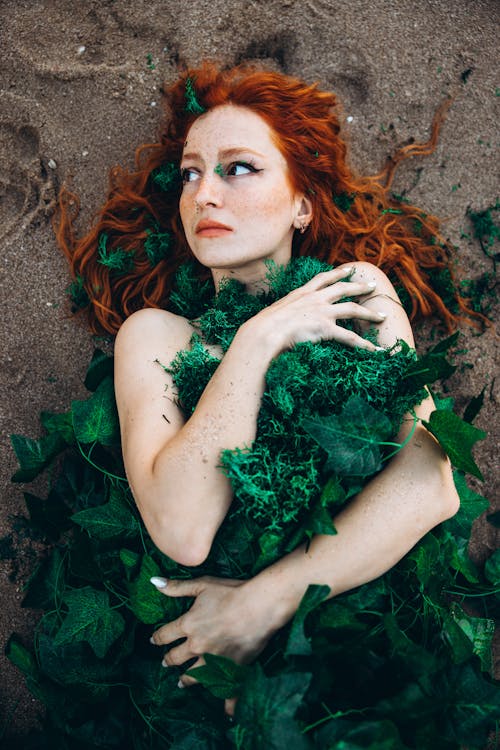 A woman with red hair and green leaves on her body