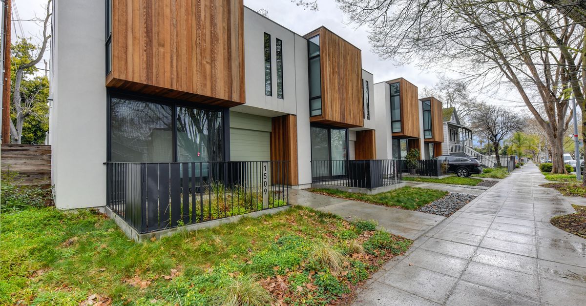 Contemporary suburban houses with wood accents in a tree-lined neighborhood.