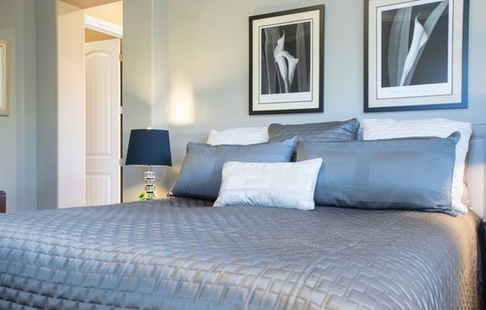 A contemporary bedroom featuring a comfortable bed, pillows, and artistic decor.