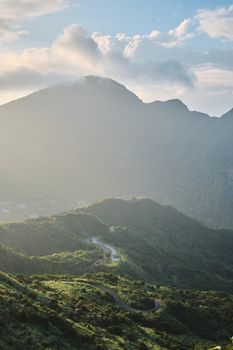 Breathtaking view of lush green hills and towering mountains in Keelung, Taiwan, under a serene sky.