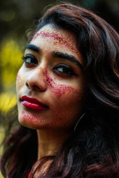 Close-up portrait of a woman with glitter makeup, showcasing vibrant beauty.