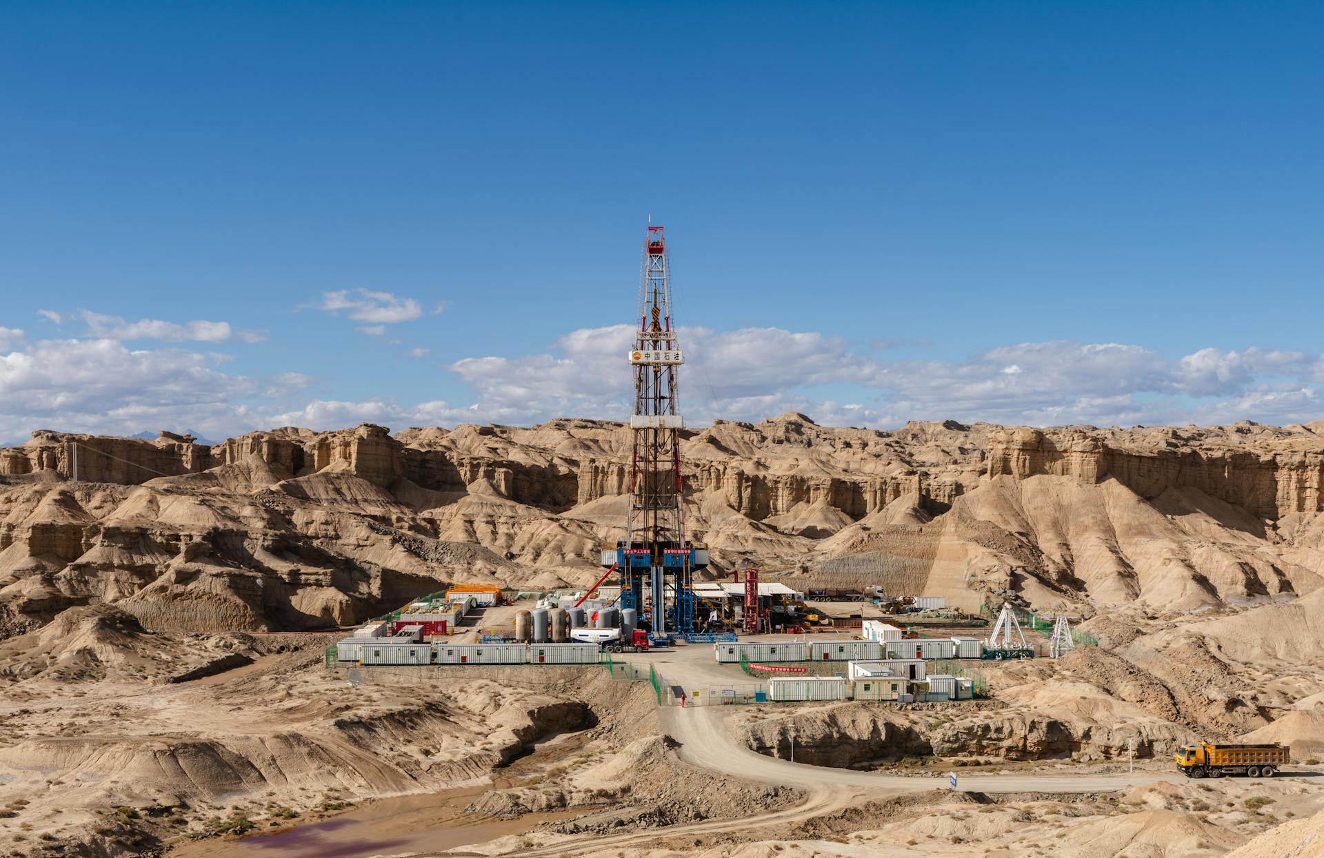 Aerial view of an oil rig amidst desert rock formations, showcasing industrial exploration.