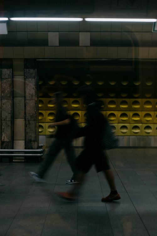 Free Blurred silhouettes of people walking through an urban subway station, capturing dynamic city life. Stock Photo