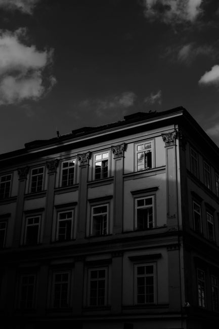 Low angle view of a shadowed building against a dramatic sky, showcasing urban architecture.