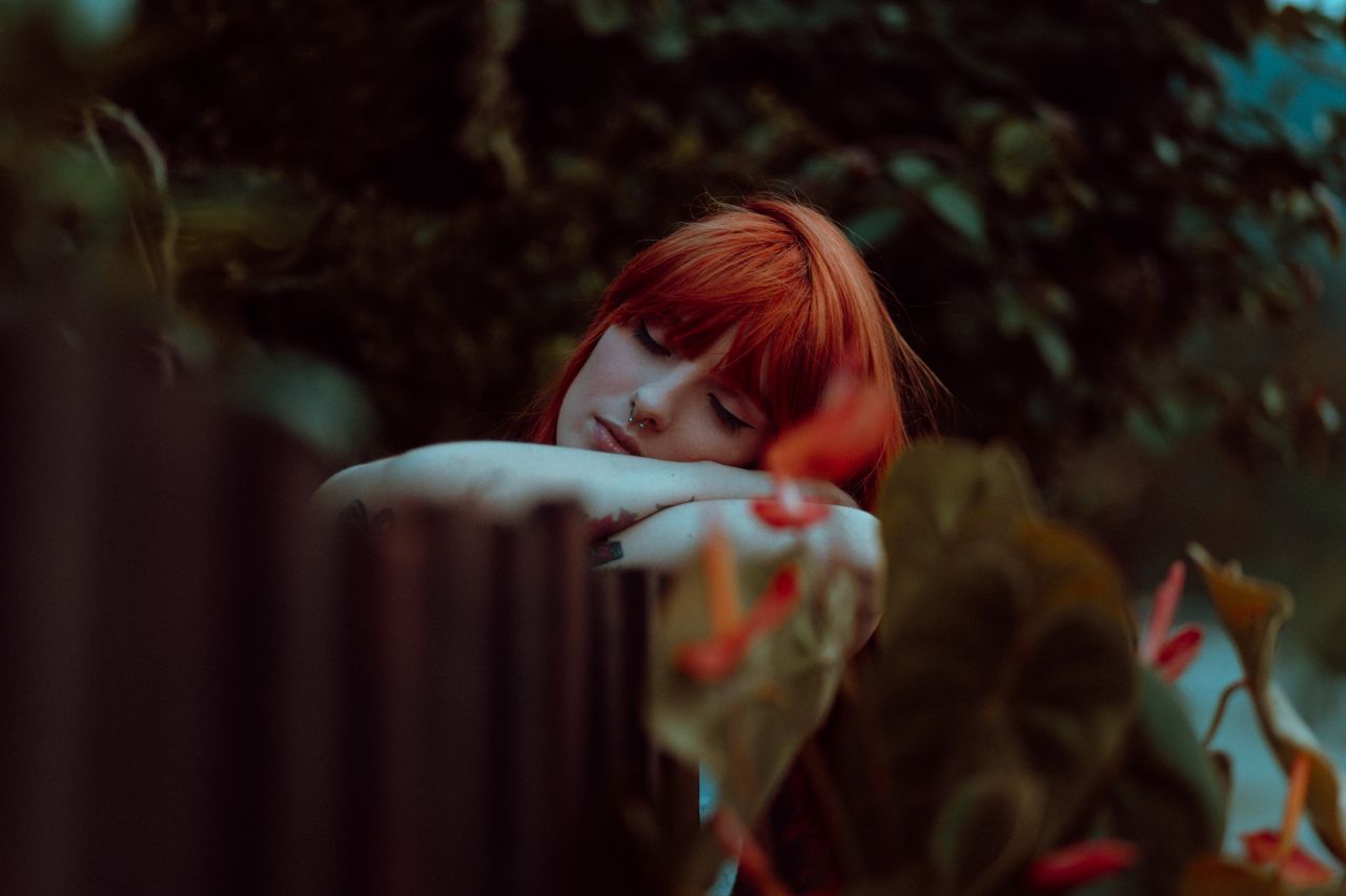 serene portrait of a redheaded woman peacefully resting outdoors surro