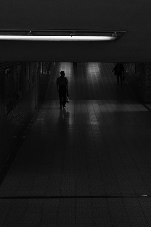 Free A lone silhouette walking in a dimly lit underground pedestrian tunnel creates a moody ambiance. Stock Photo