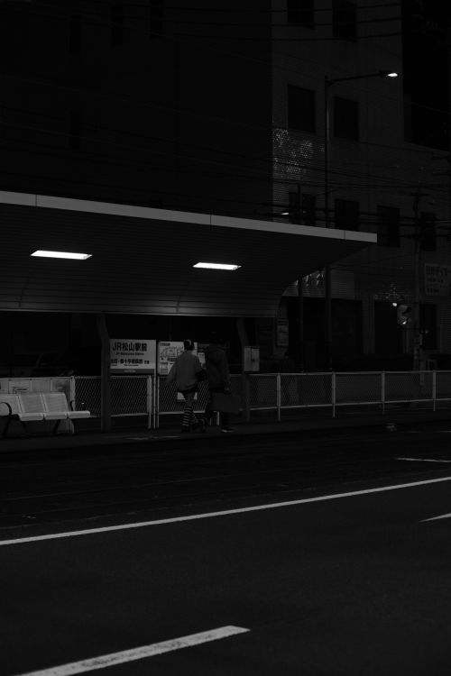 Free A moody black and white photo of people at a nighttime urban train station. Stock Photo
