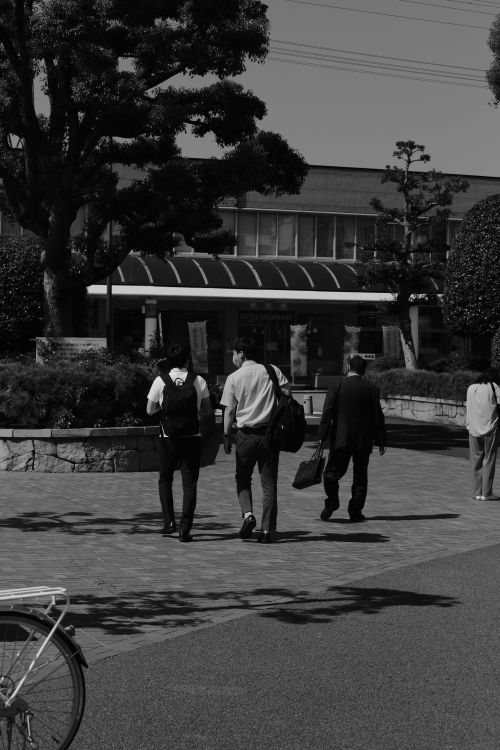 Free Black and white urban scene of pedestrians walking on a sidewalk near a building. Stock Photo