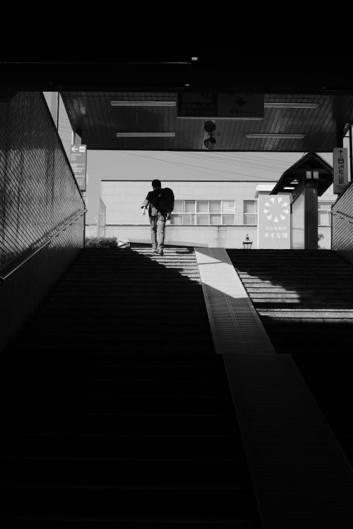 Free Black and white urban scene featuring a person in silhouette on subway stairs. Stock Photo