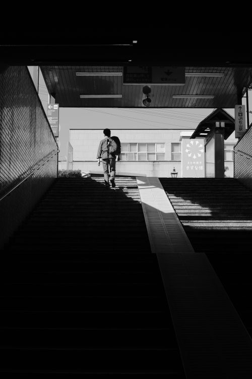 Free Black and white silhouette of a person walking up stairs in a city setting. Stock Photo