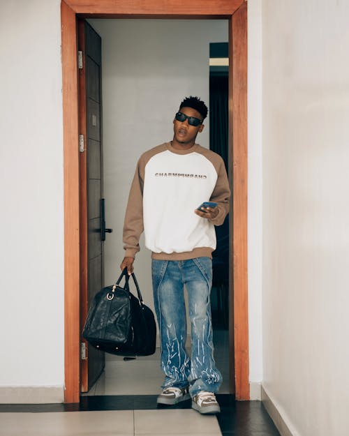 A man in a sweatshirt and jeans holding a bag