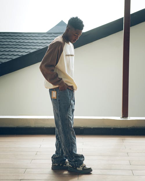 A man in jeans and sneakers standing on a wooden floor