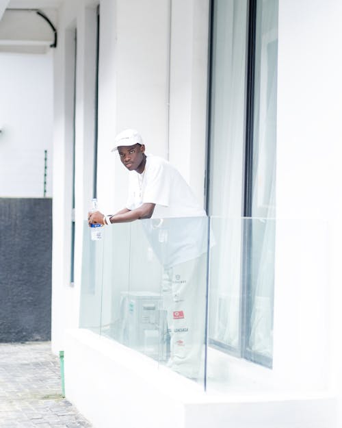 A man in white hat leaning on a balcony