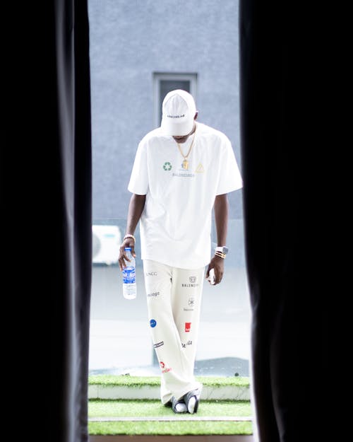 A man in white pants and a hat is standing in a doorway