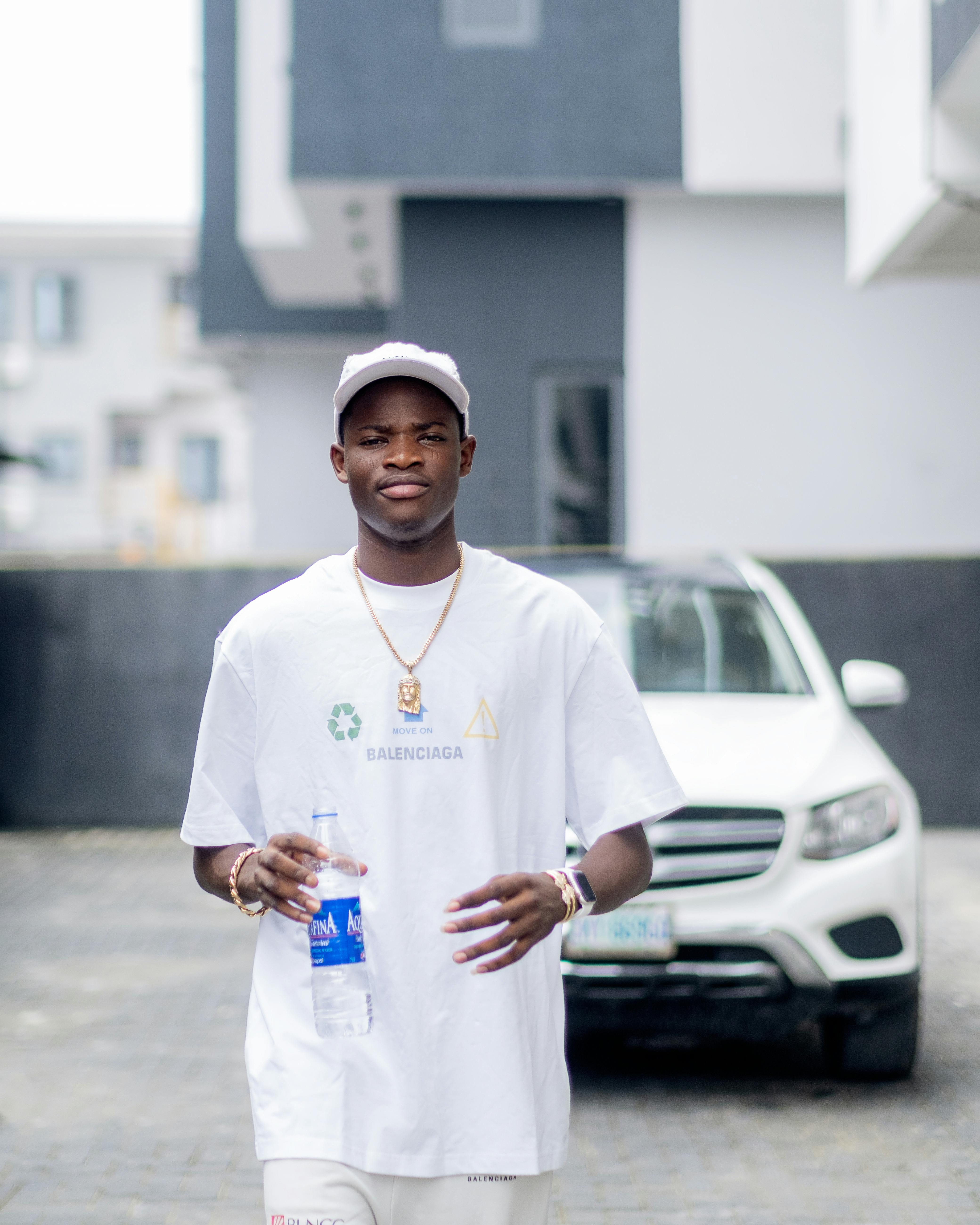 a man in white shirt and white hat standing in front of a car