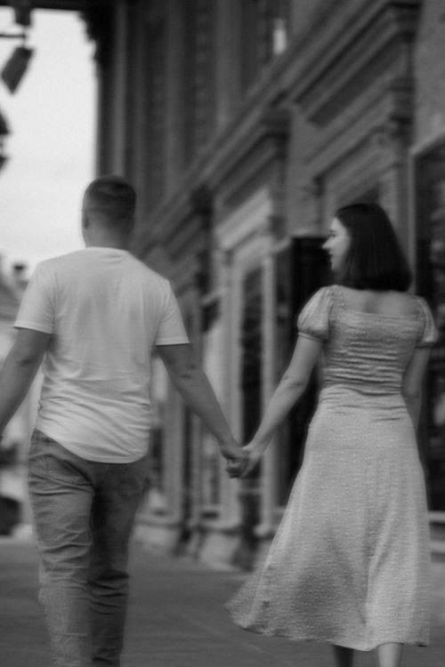 Free A couple holding hands walks down a historic street in Ternopil, Ukraine, in a black and white photo. Stock Photo