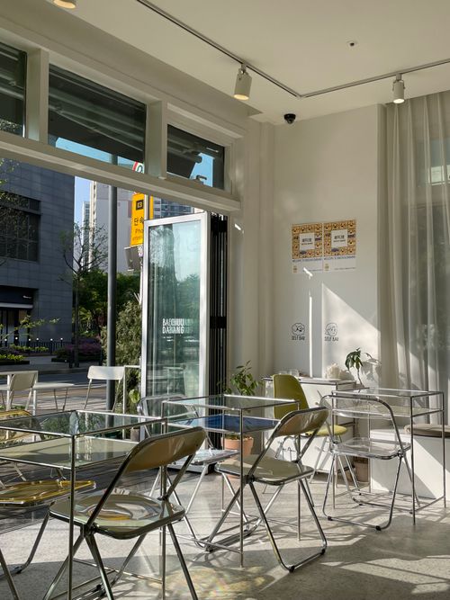 Free Sunny and inviting café interior with glass tables and clear chairs, perfect for a morning coffee. Stock Photo