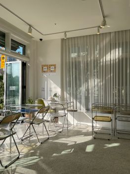 Sunlit modern café with minimalist design featuring chairs and tables.