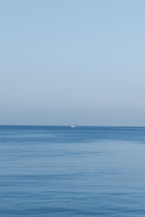 Free A tranquil view of the ocean in Toyohashi, Japan, with a lone boat on the horizon. Stock Photo