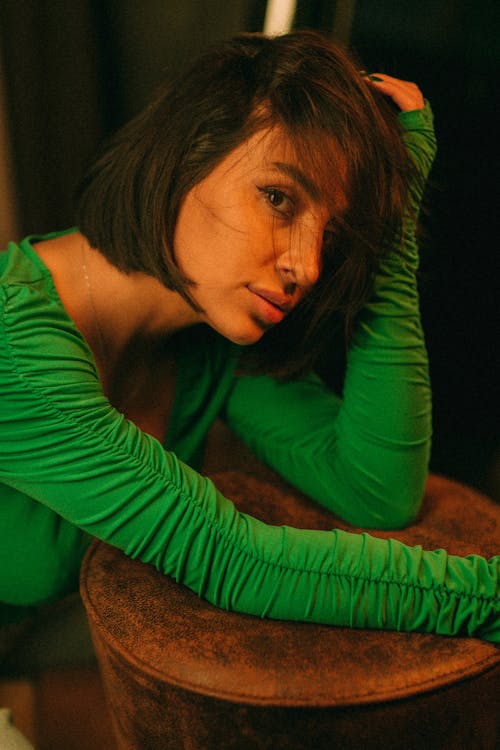 A woman in a green shirt sitting on a stool