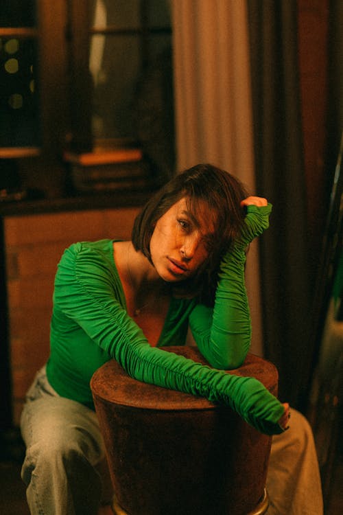A woman in a green shirt sitting on a stool