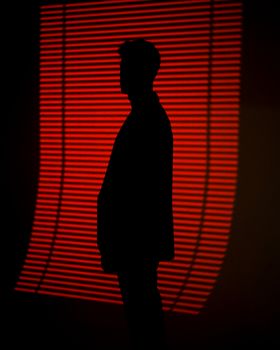 一个人站在带有水平线条的醒目红灯背景前的轮廓。 - 相关推荐