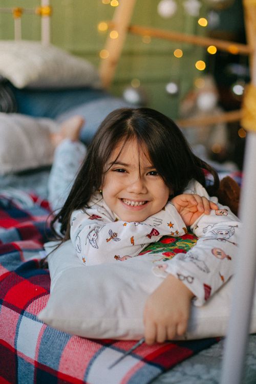 A young girl laying on a bed with christmas lights · Free Stock Photo