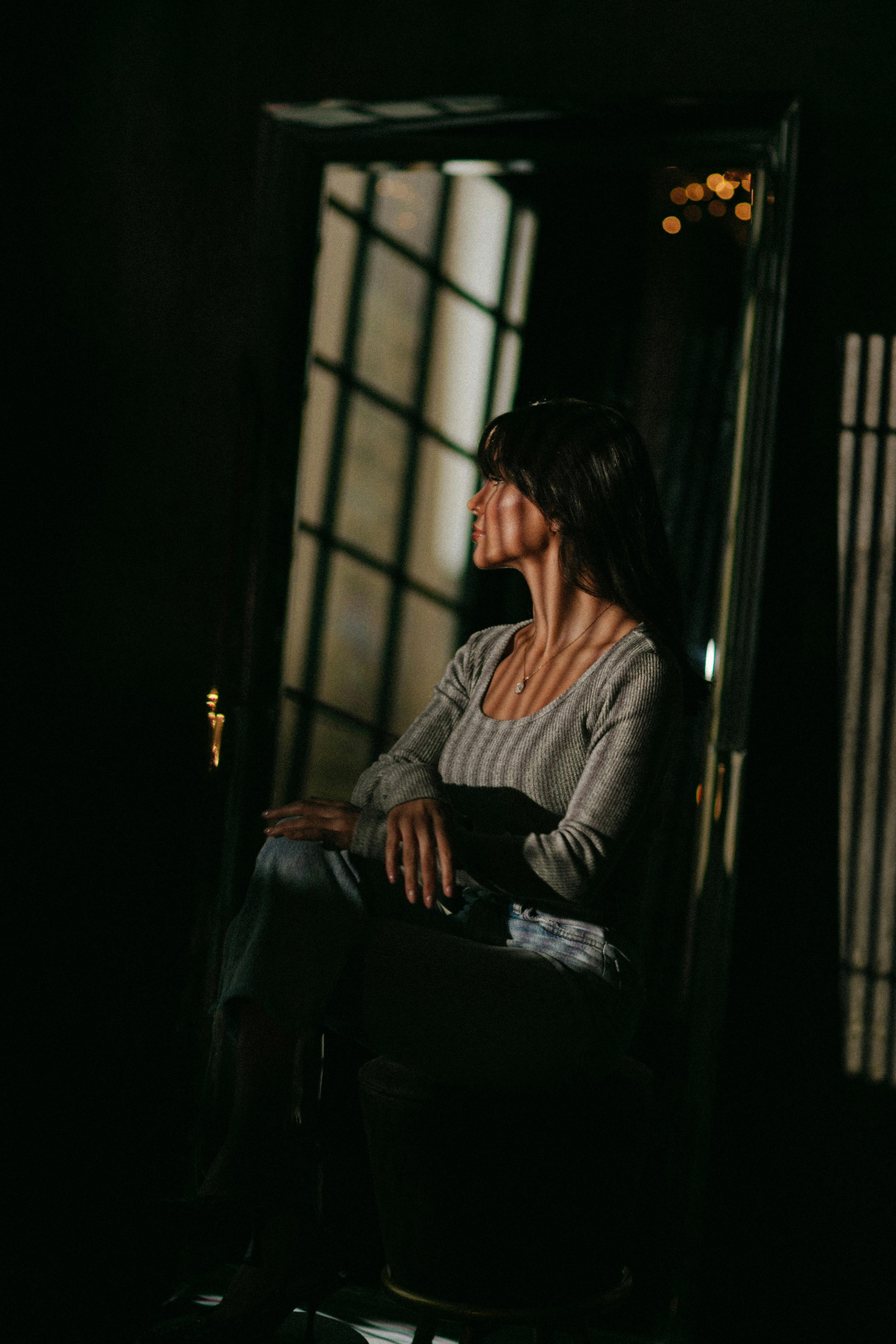 Artistic portrait of a woman in dramatic light indoors, evoking emotion and introspection.
