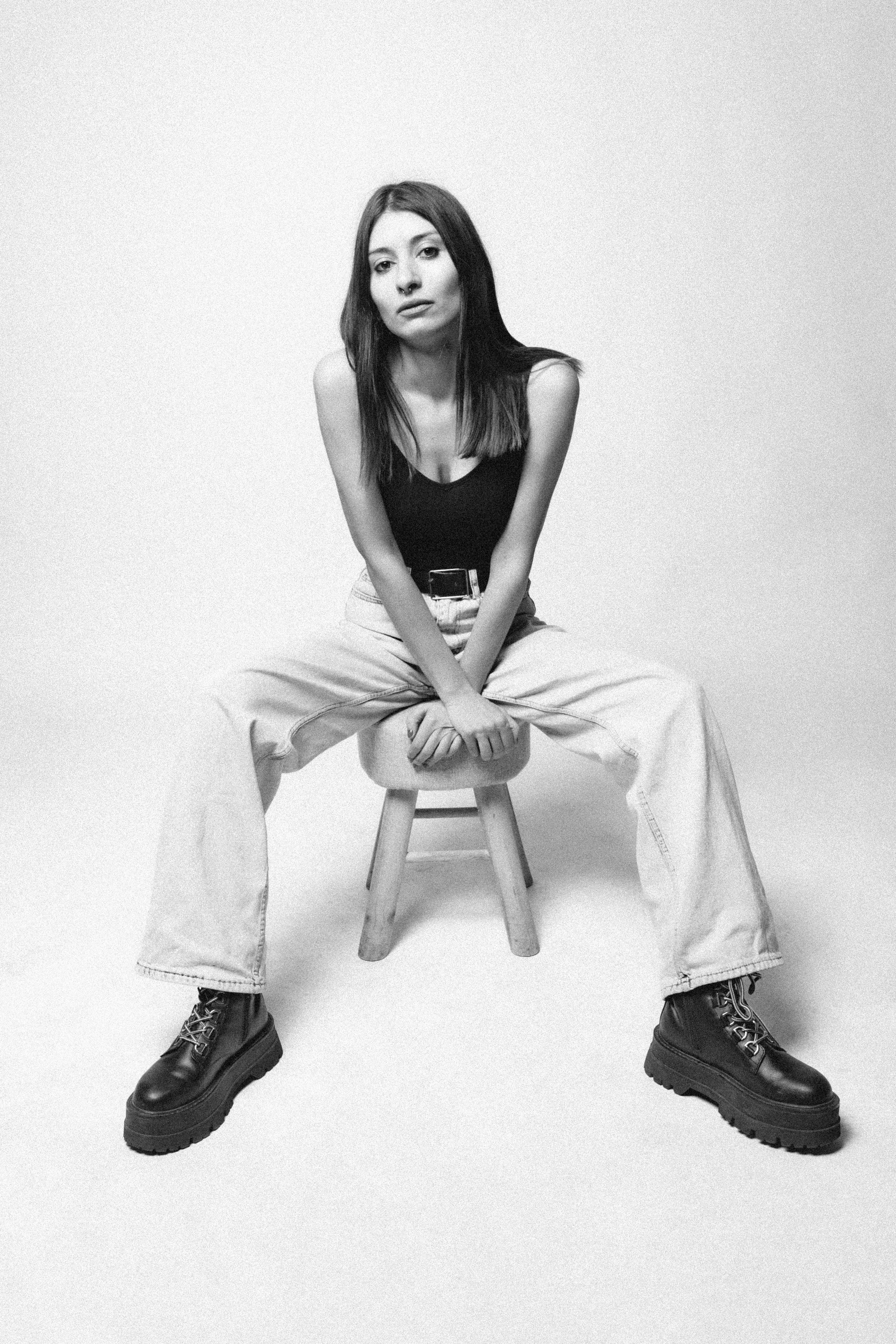 Bezpłatne Stylowa młoda kobieta siedzi pewnie na czarno-białym portrecie. Zdjęcie z galerii