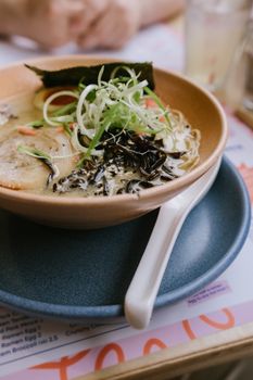 Delicious ramen bowl with pork, seaweed, and green onions, styled elegantly on a table.