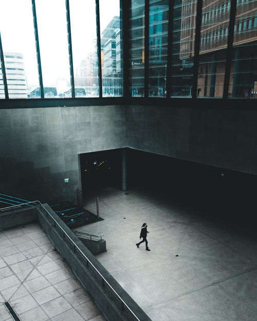 Free A solitary person walks within a contemporary architectural space in Berlin, highlighting modern urban design. Stock Photo