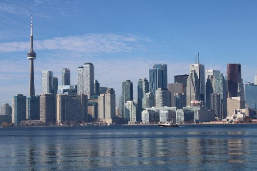 Toronto skyline with CN Tower and skyscrapers reflecting on Lake Ontario.