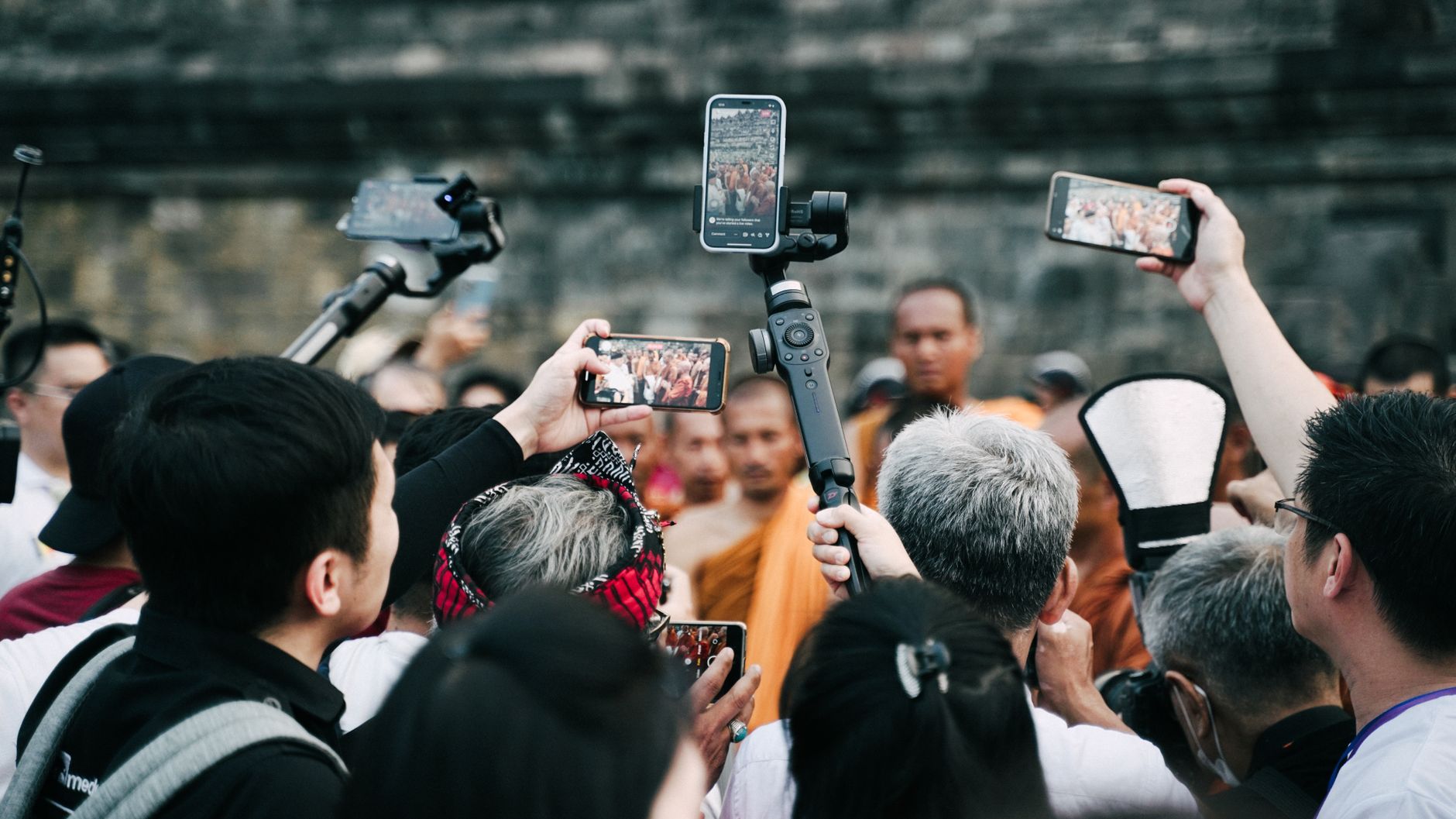 廟宇拍照禮儀:關閉手機快門聲與音量全攻略 A crowd uses smartphones to capture a Buddhist ceremony at a historic site.