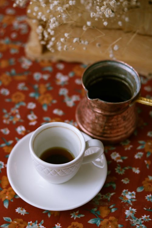 Free A stylish coffee scene with a cup and copper pot on floral tablecloth. Stock Photo
