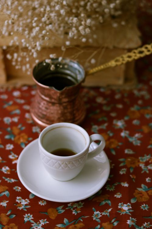 Free A traditional Turkish coffee set with a copper cezve and ornate cup on a floral tablecloth. Stock Photo