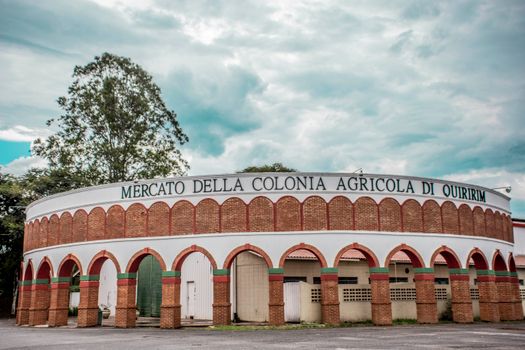 Exterior of Mercato della Colonia Agricola di Quiririm with cloudy sky above.