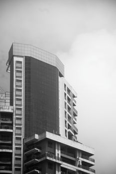 Black and white photo of a modern high-rise building against the sky, showcasing urban architecture.